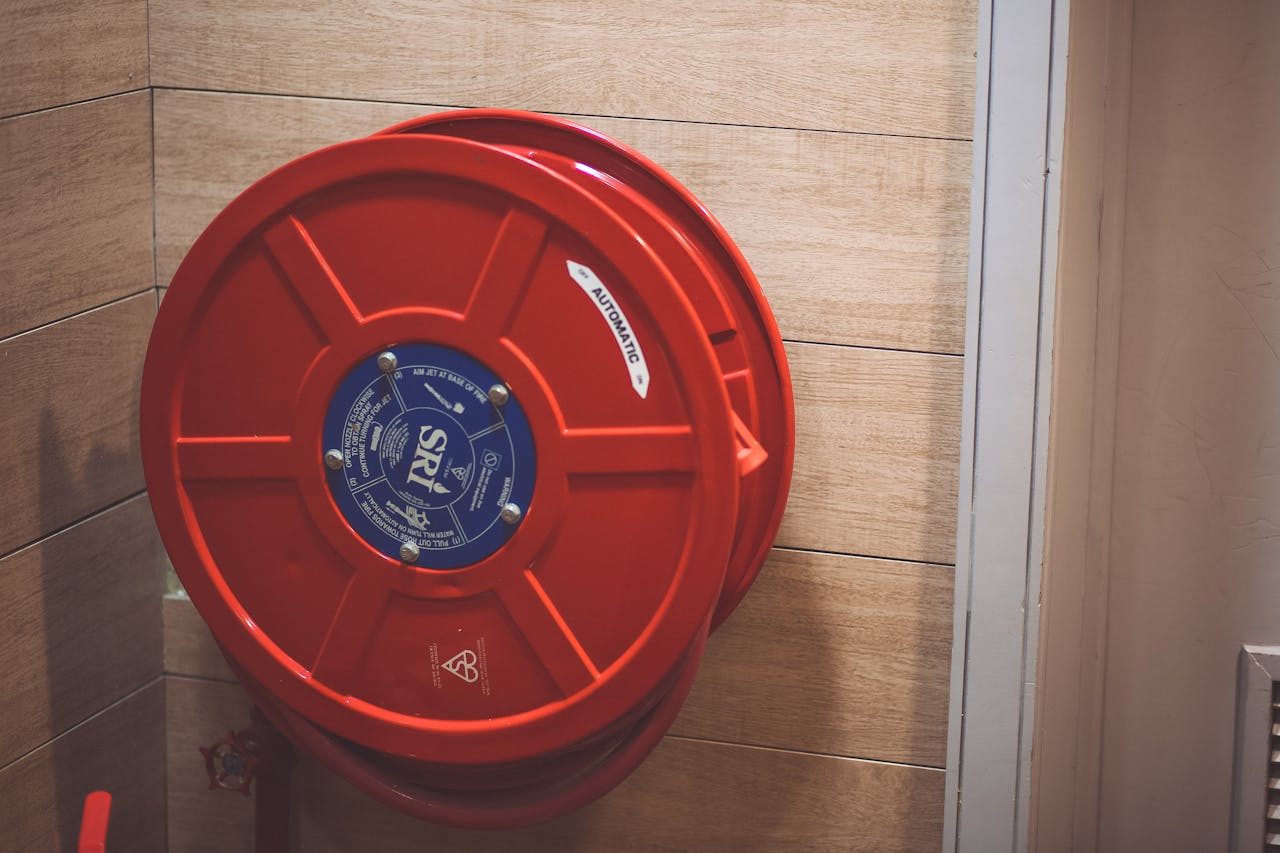 about-img A red fire hose reel mounted on a wooden wall indoors for safety.