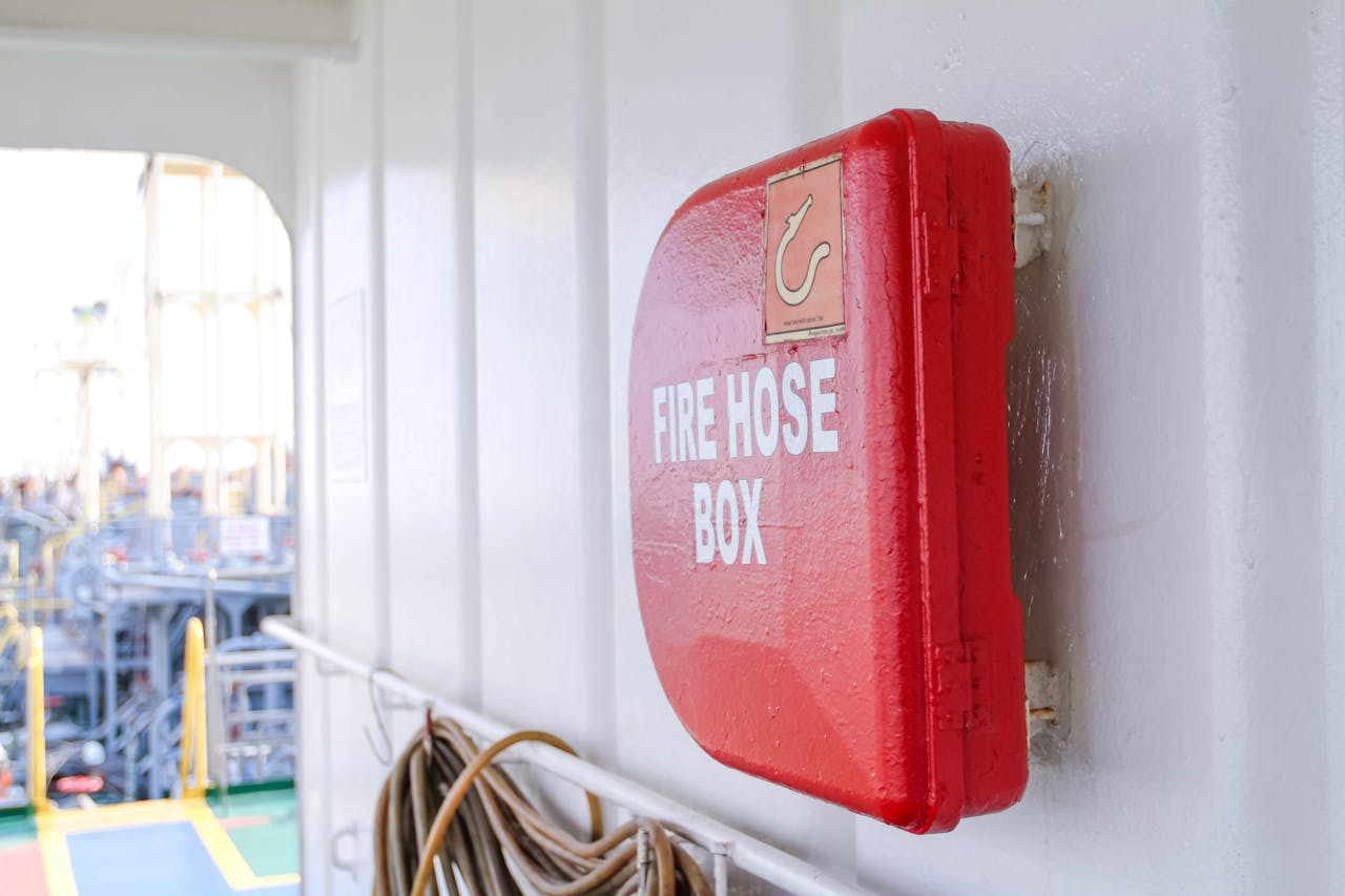 our-services-05 Close-up of a bright red fire hose box on a ship deck, emphasizing safety.
